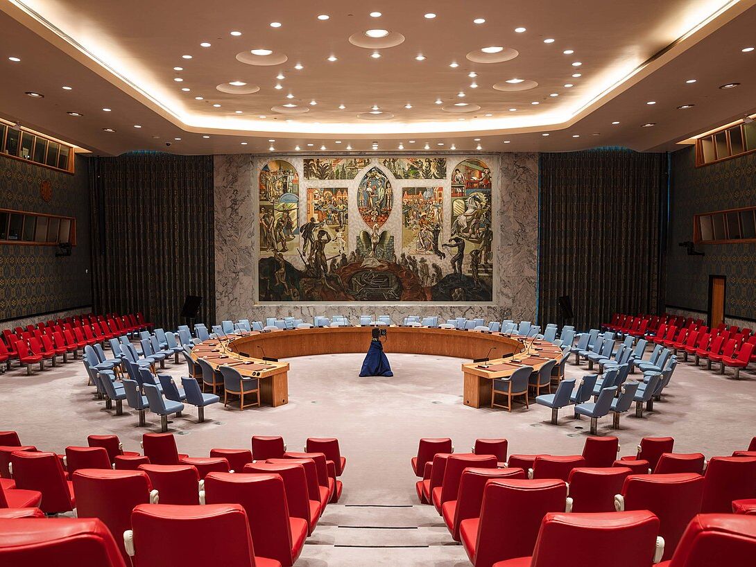 纽约联合国安理会会议厅内景，马蹄形会议桌与壁画