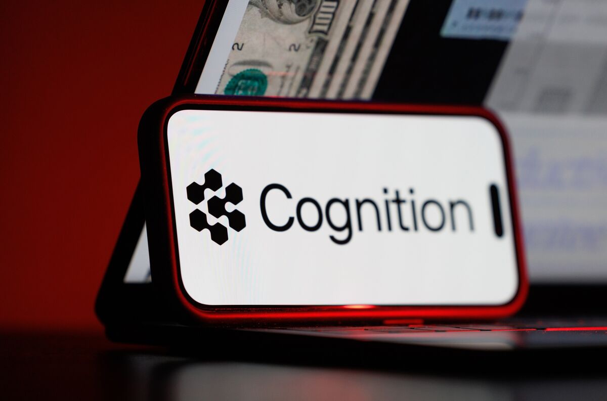 显示 Cognition 公司标志的手机与显示美元图案的笔记本电脑，Bloomberg 报道配图