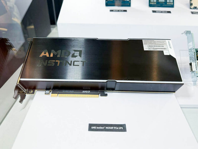 展台上的 AMD Instinct MI350P PCIe 卡，前方标牌写明产品名称（ServeTheHome 摄）