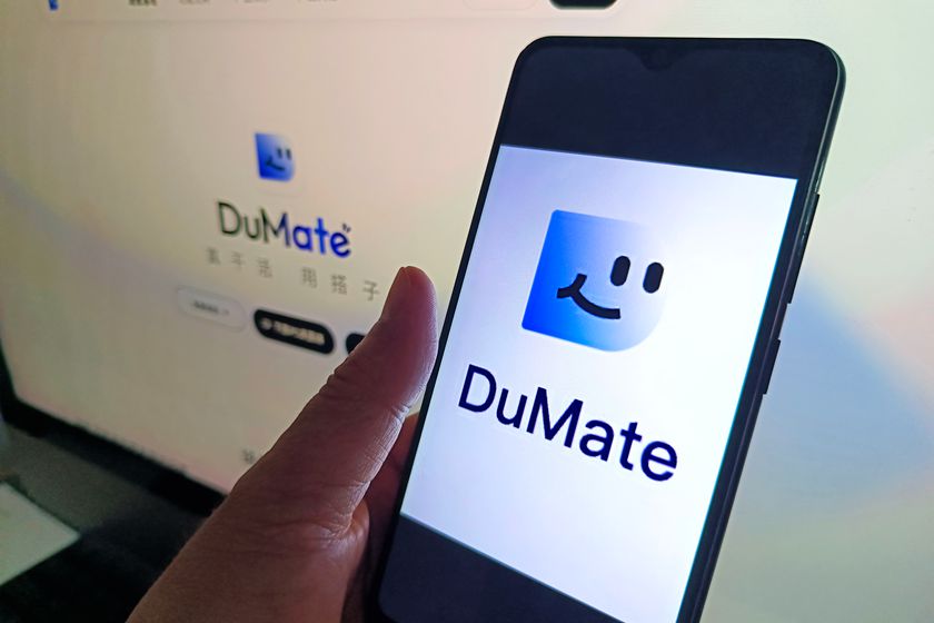 手机屏幕上显示百度搭子（DuMate）应用的启动页，背景显示器上为百度搭子官网页面