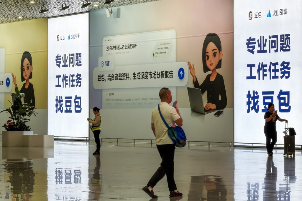 旅客走过深圳宝安国际机场内豆包AI助手平台的广告牌，2026年5月16日。图源：Cheng Xin/Getty Images