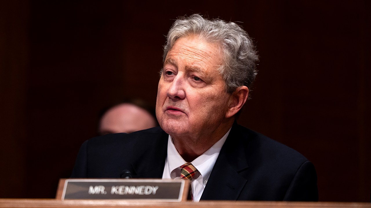 参议员 John Kennedy 在参议院听证会上，桌牌写着 MR. KENNEDY