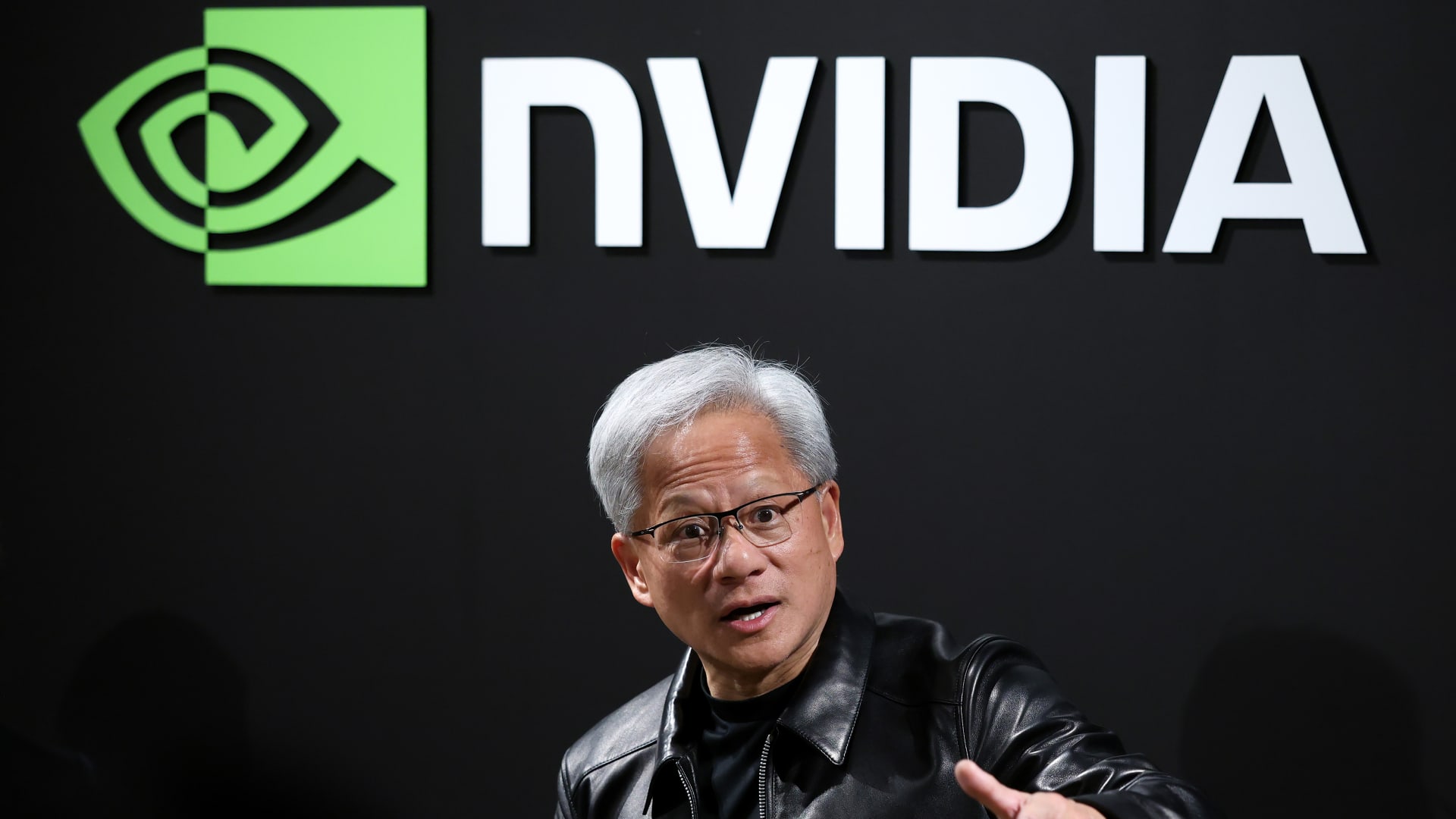 英伟达 CEO 黄仁勋站在 NVIDIA 标识前