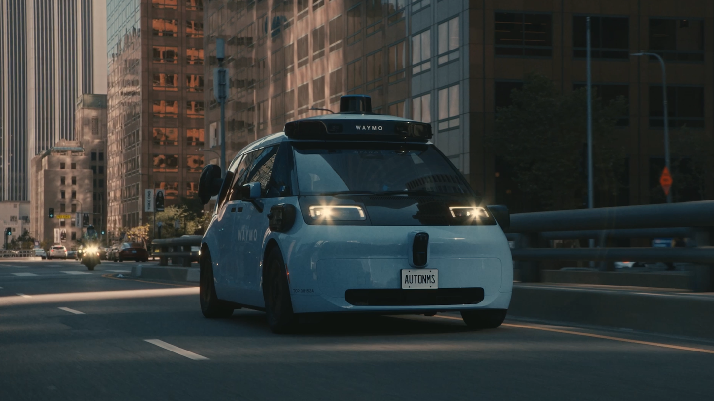 Waymo 官方宣传图：白色 Waymo 自动驾驶车辆行驶在城市街道上