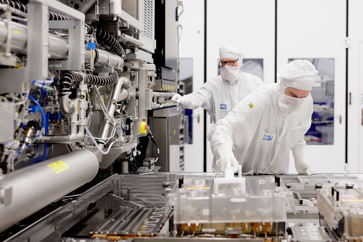 半导体厂洁净室中、光刻设备旁处理掩模载具的技术人员（彭博报道配图）