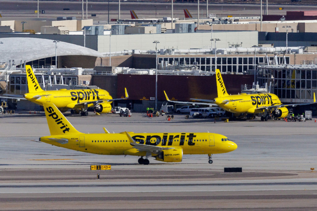 精神航空（Spirit Airlines）的黄色涂装飞机停在机场停机坪，机身上可见 spirit 字样（Reuters 图片，via PBS News）