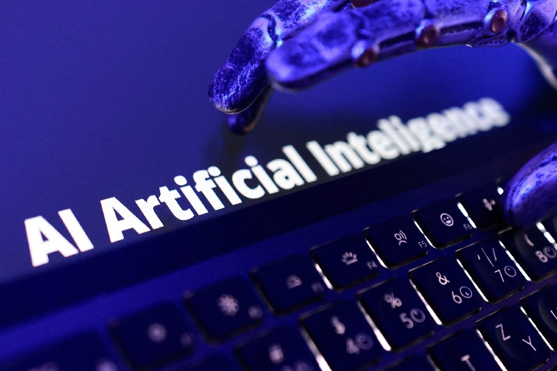 AI 题材配图：金属机械手伸向笔记本电脑键盘，画面上有 AI Artificial Intelligence 字样
